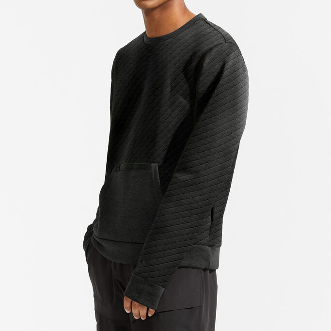Jeune homme vu de côté, la main dans les poches, montrant la manche du pull.