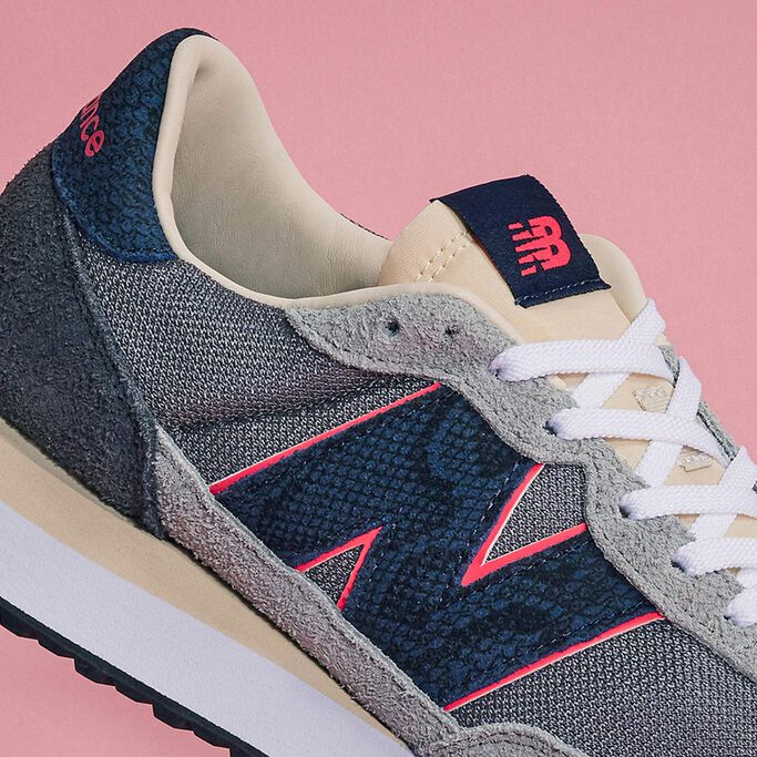 Une image agrandie d'une chaussure de sport 'Blue Racer' 237 NB x SNS grise et bleu marine sur un fond de couleur rose feutrée