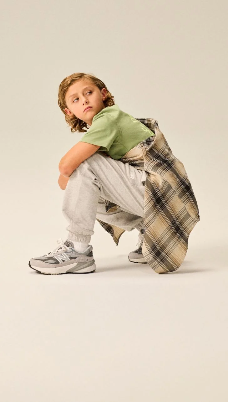 Boy wearing a pair of 990v6 shoes.