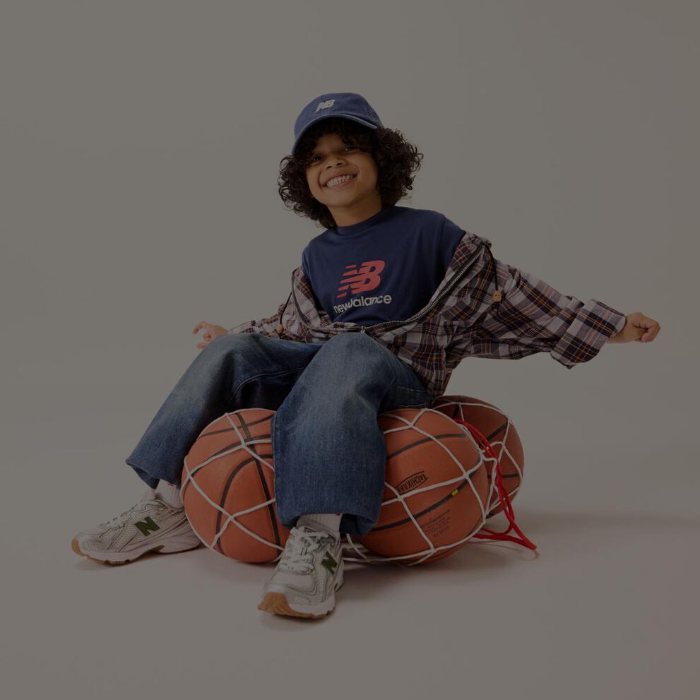 Un enfant assis sur un filet de ballons de basket.