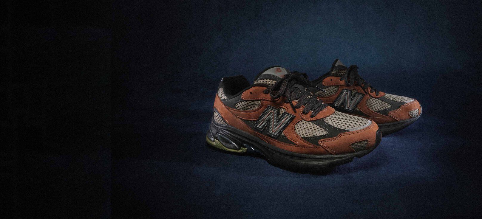 A brown pair of ABZORB 2010 sneakers sitting on a blue studio backdrop.