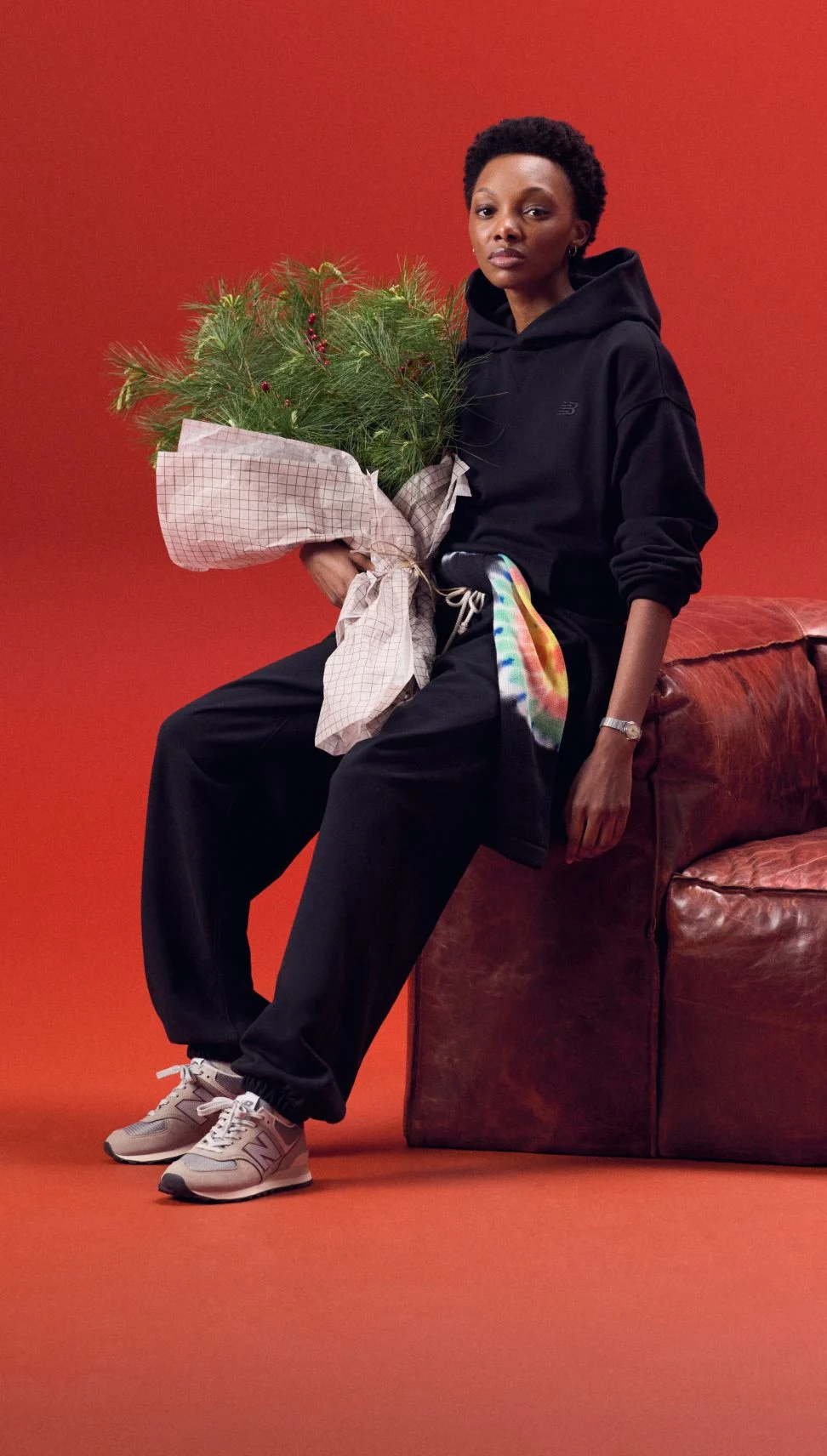 Jeune femme en ensemble noir assorti tenant des vêtements verts.