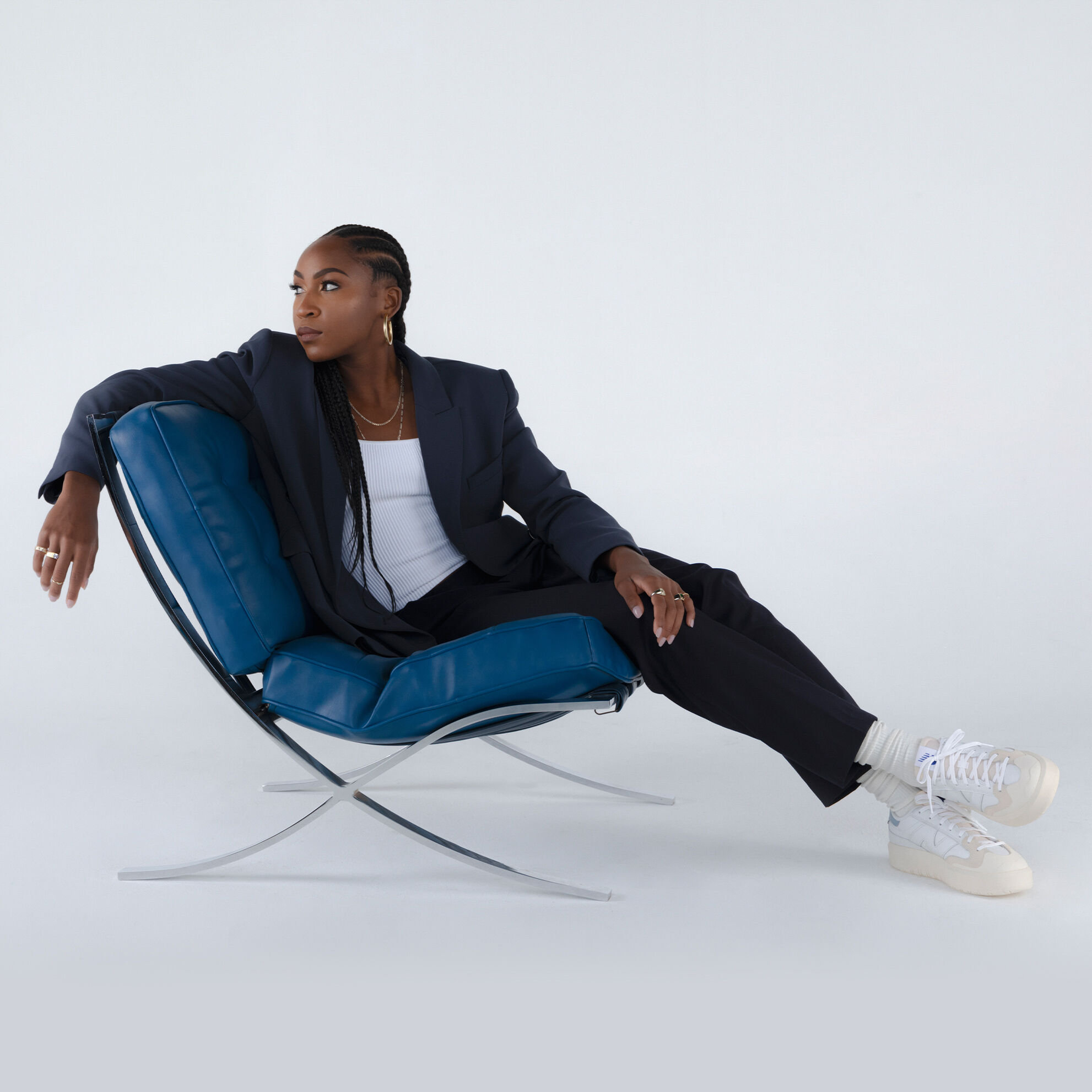 La star de tennis, Coco Gauff, assise sur une chaise bleue et portant une paire de chaussures CT302