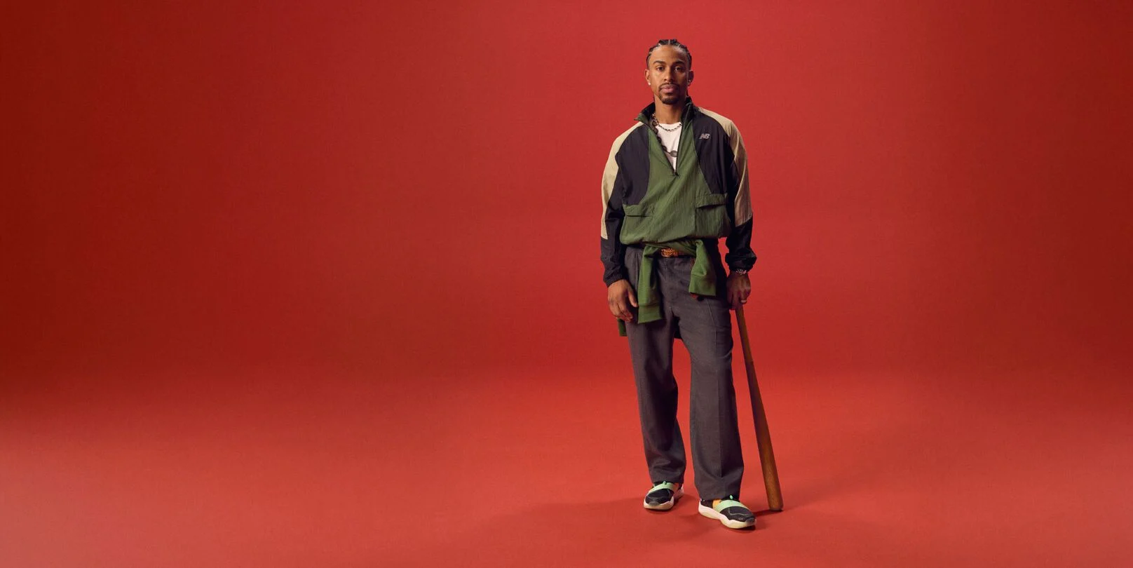 Athlète de baseball tenant une batte sur fond rouge.