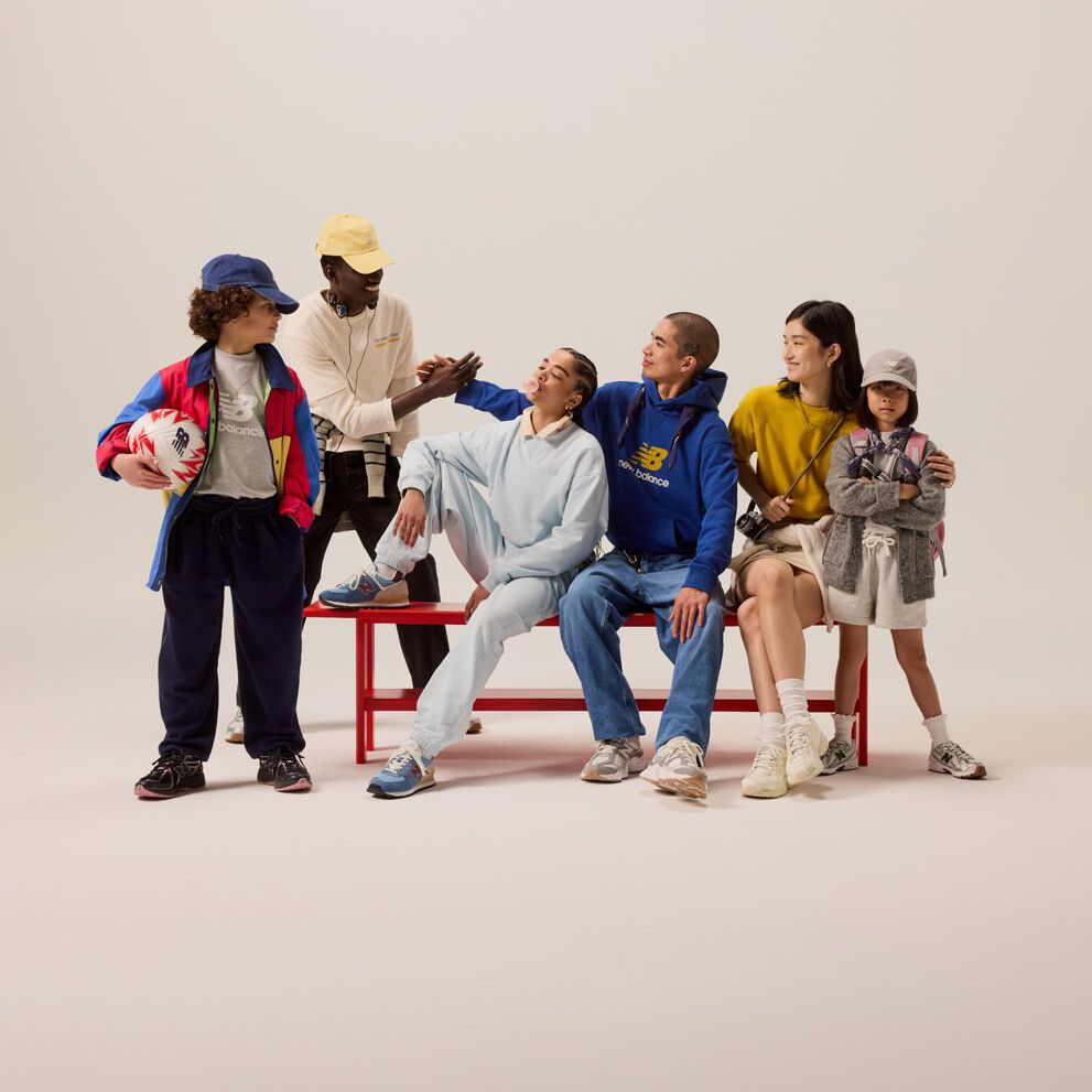 Groupe d'étudiants assis sur un banc rouge devant un fond beige. 