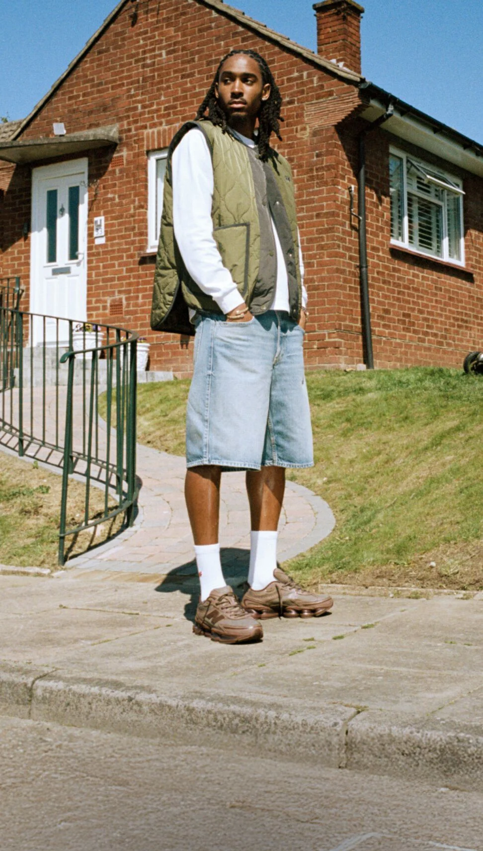 Knee-down image of someone wearing grey New Balance sneakers outdoors.