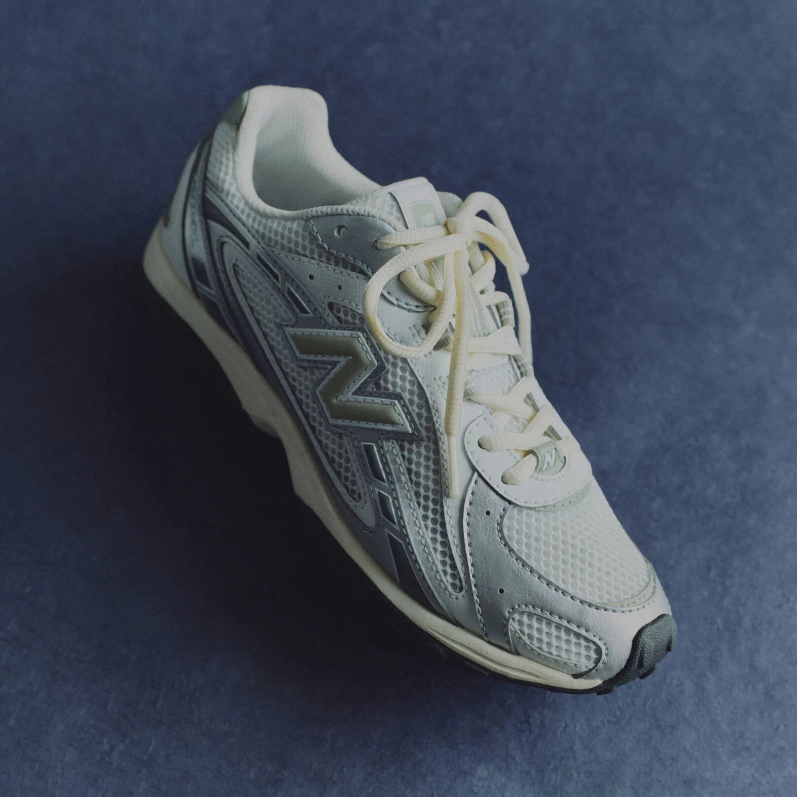 Une chaussure argentée posée sur un fond bleu de studio.