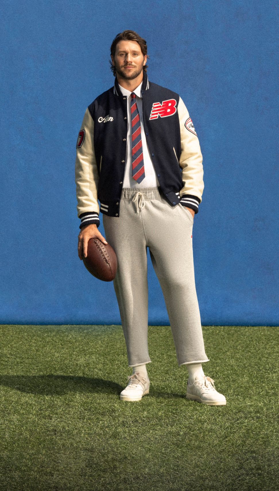 Young athlete standing on a field with a blue background wearing a custom jacket.
