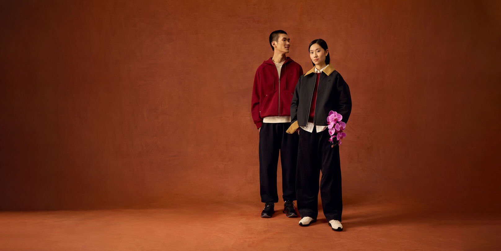 Man and woman standing up with the woman holding flowers. 