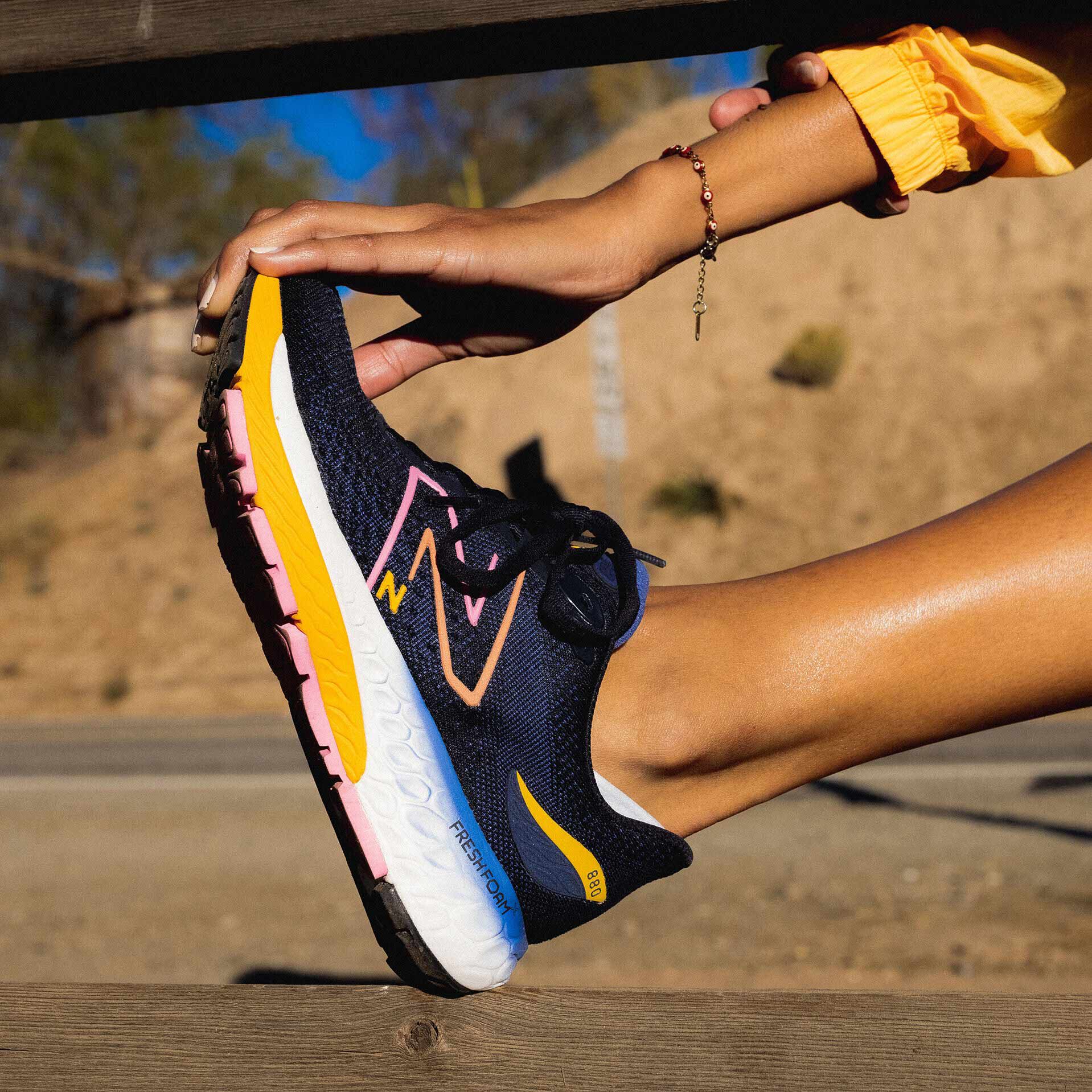 Person stretching in blue Fresh Foam 880v12 shoe.