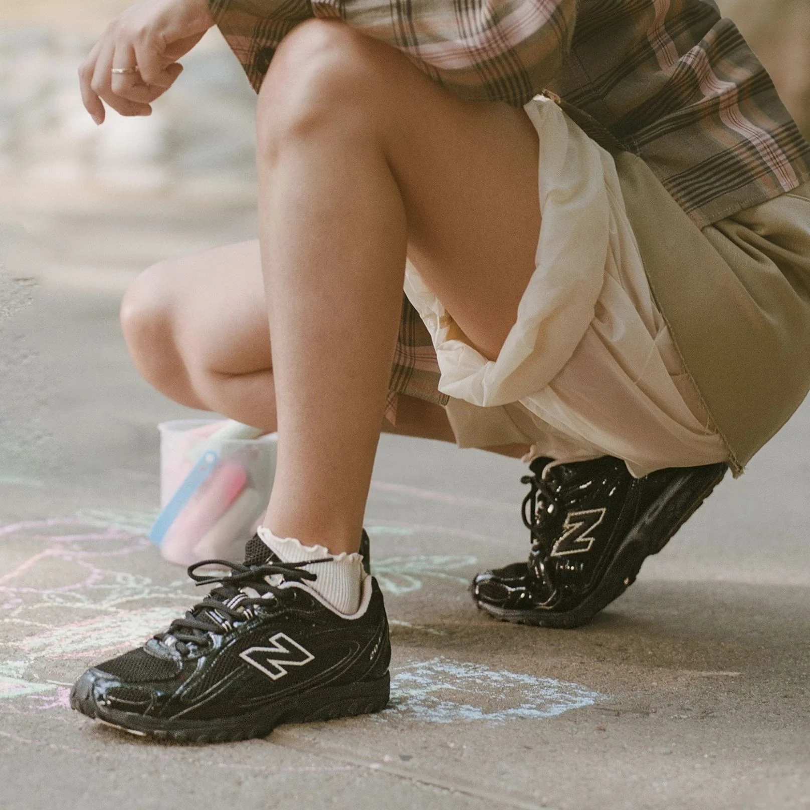 Knee down of a woman wearing black 204L shoes outside.