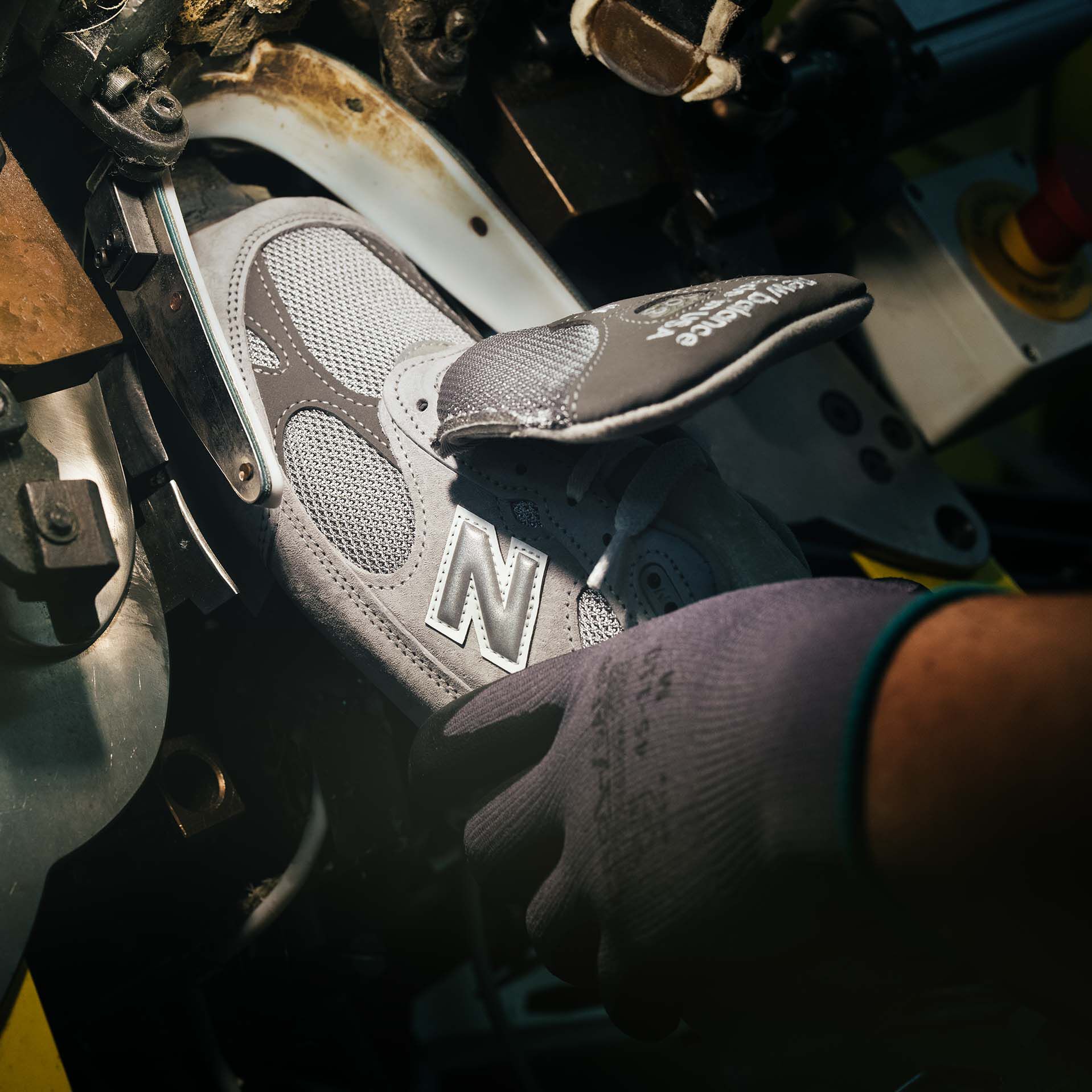 A hand putting a sneaker into a machine during it’s construction.