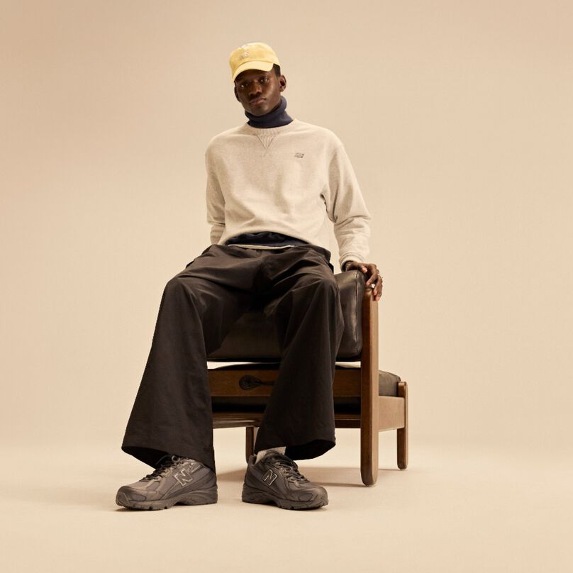 Un homme assis sur une chaise avec un fond beige.