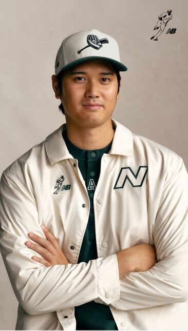 Ohtani wearing a white hat and jacket with his arms folded and smiling.