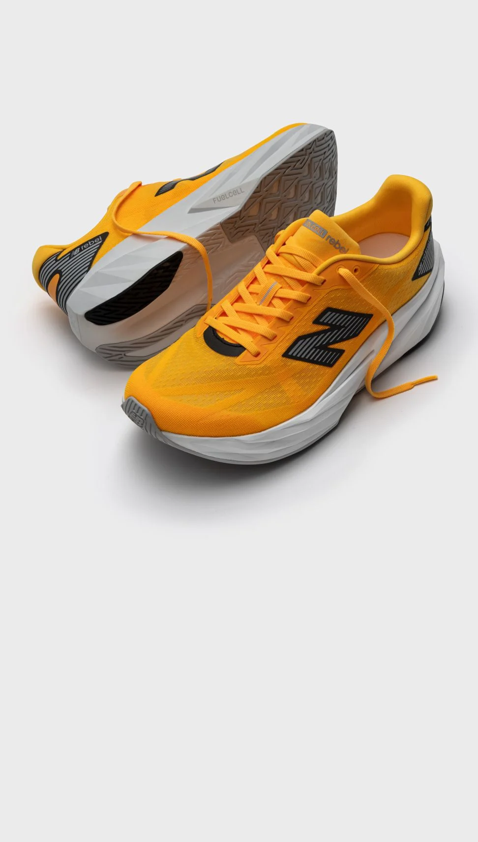 Une paire de chaussures orange FuelCell Rebel sur un fond gris.&nbsp;