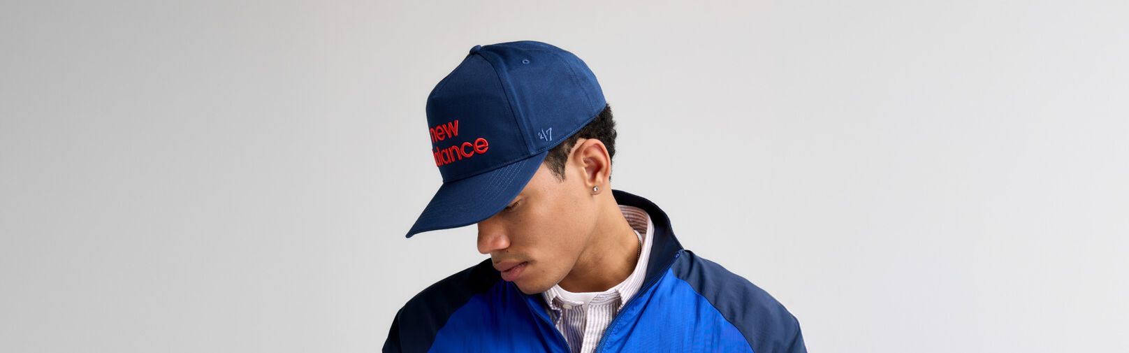 Un gros plan d&rsquo;un homme regardant sur le c&ocirc;t&eacute; tout en portant un chapeau bleu marine de '47.