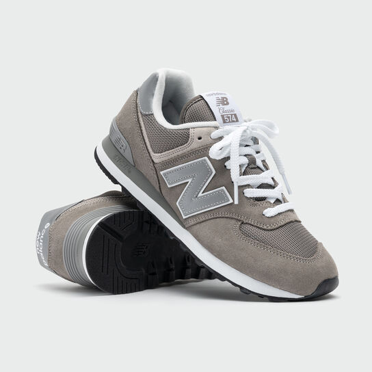 Deux chaussures 574 de couleur grise sur un fond de studio gris surimposées l'une sur l'autre.