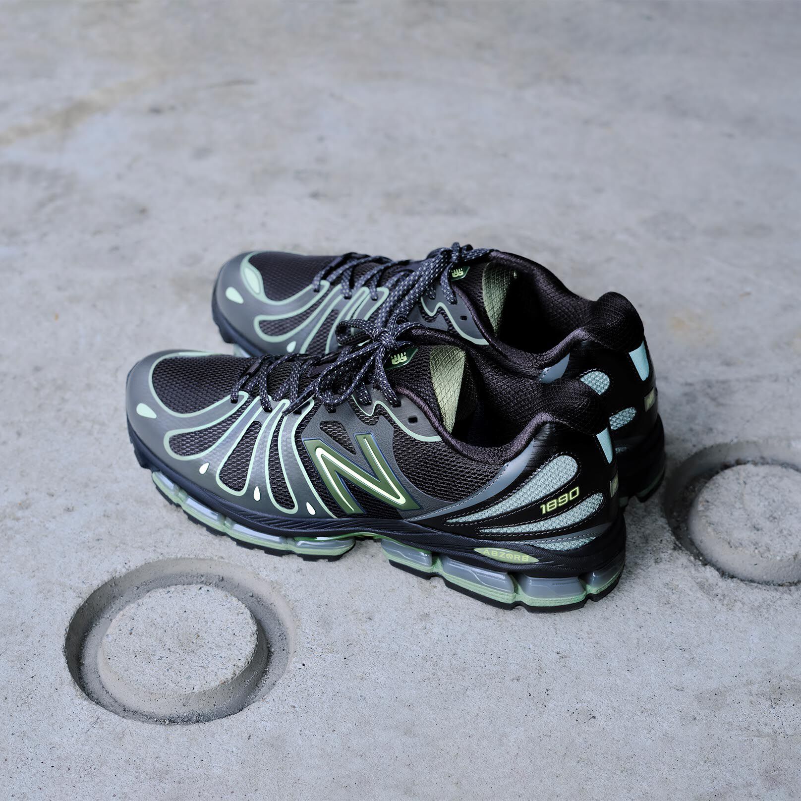 Off figure shot of a pair of lime green and black shoes on concrete with circles.