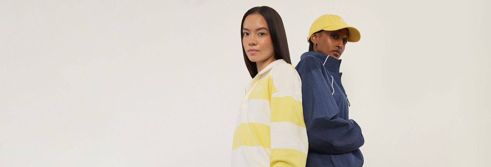 Deux femmes debout dos &agrave; dos, regardant le spectateur.