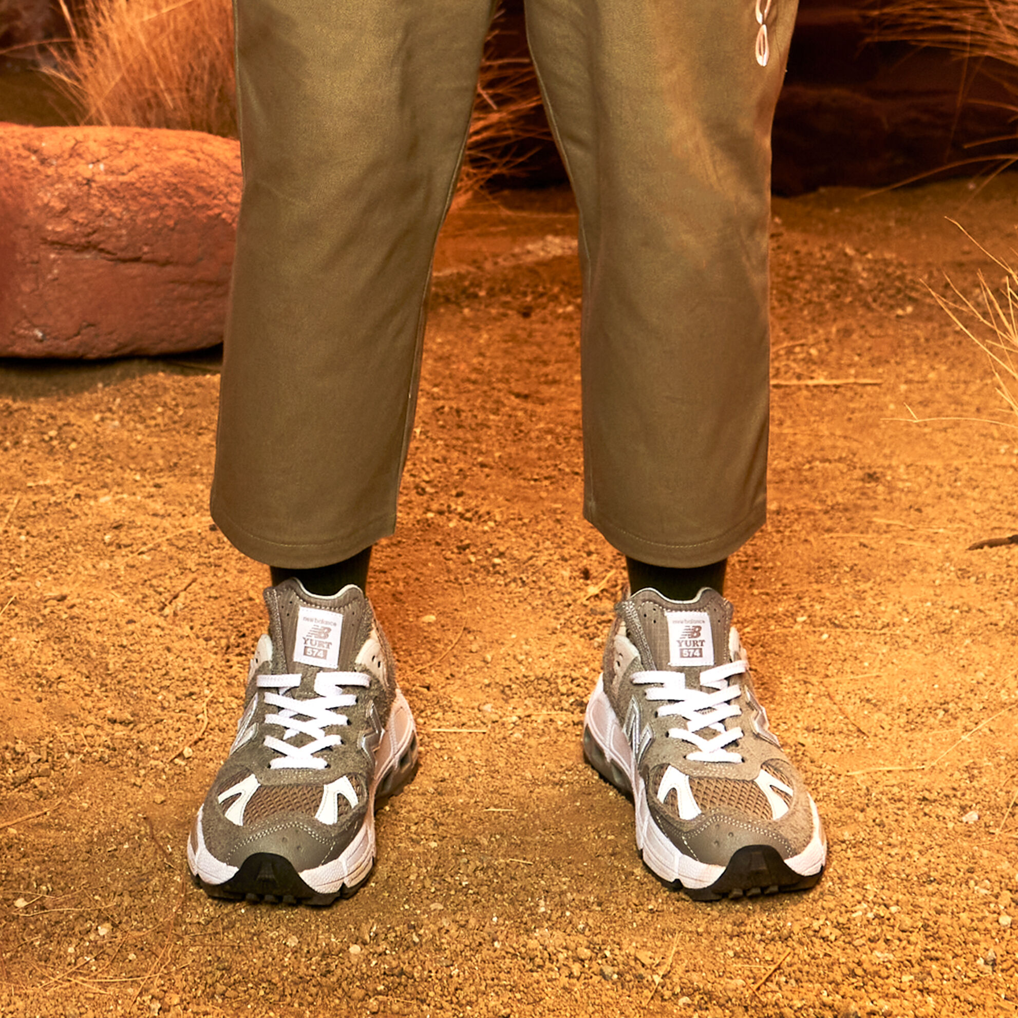 Young model wearing brown pants standing in dirt.