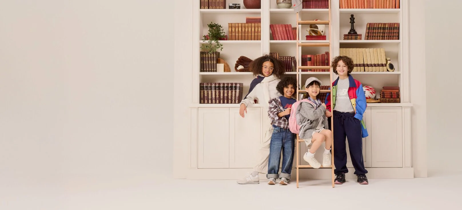 Group of young kids standing in front of a bookshelf. 
