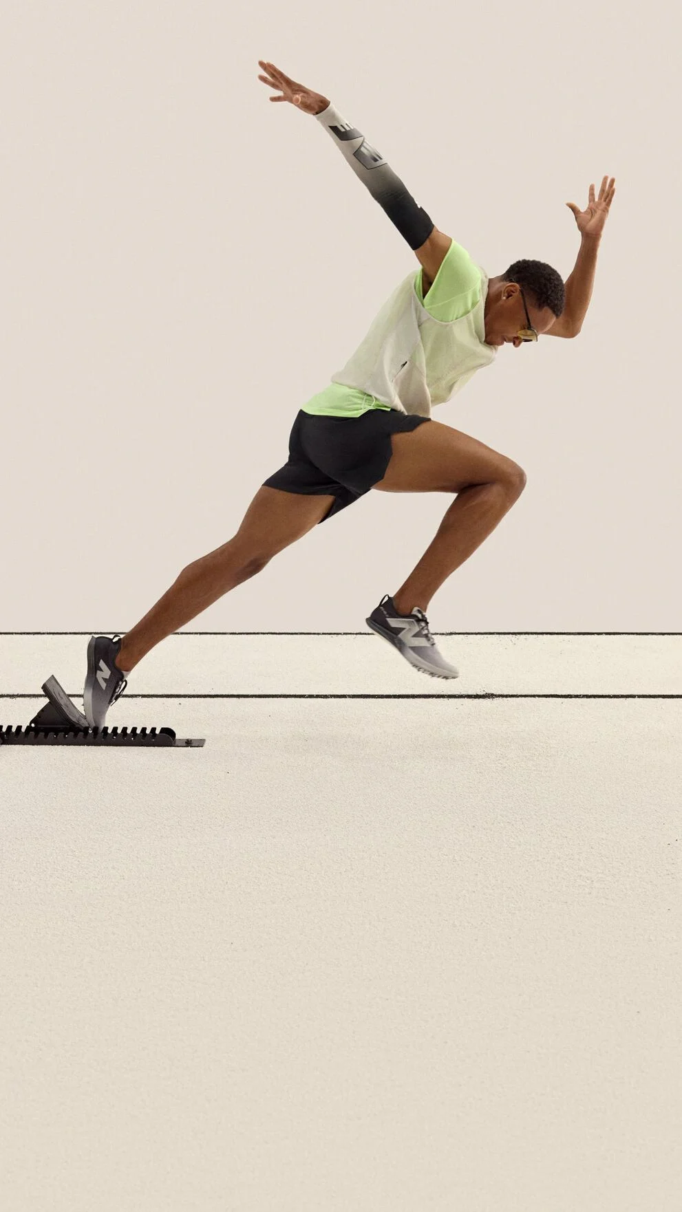 A sprinter is captured mid-stride launching from starting blocks on a track. 
