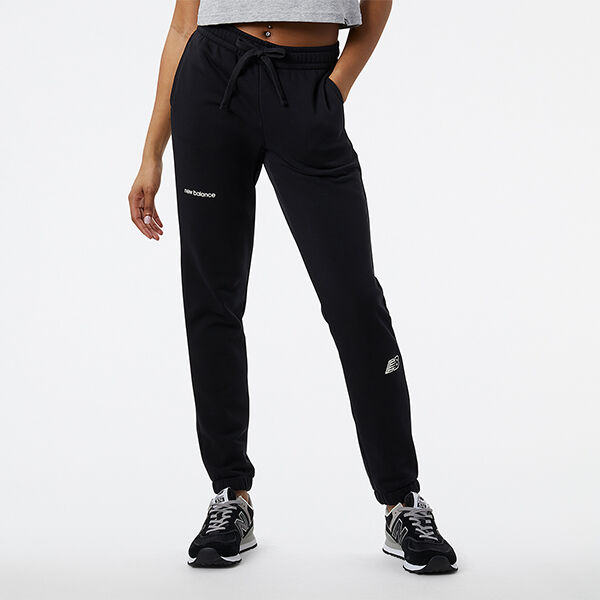 Image d'une femme, de la taille vers le bas, portant un pantalon de survêtement NB noir et des chaussures de sport NB 574 noires/grises