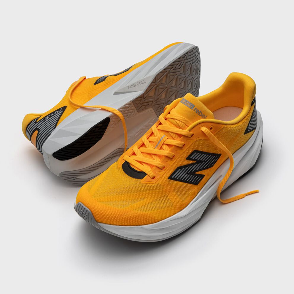 A pair of orange FuelCell Rebel shoes on a grey background. 