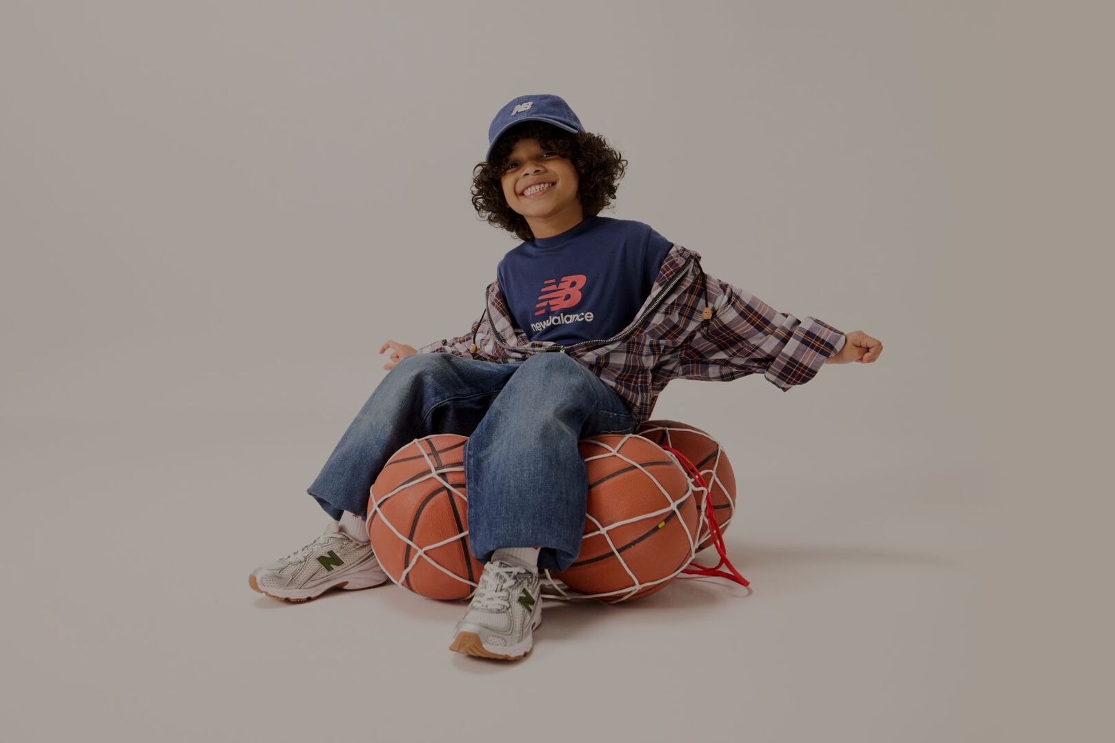Un enfant assis sur un filet de ballons de basket.