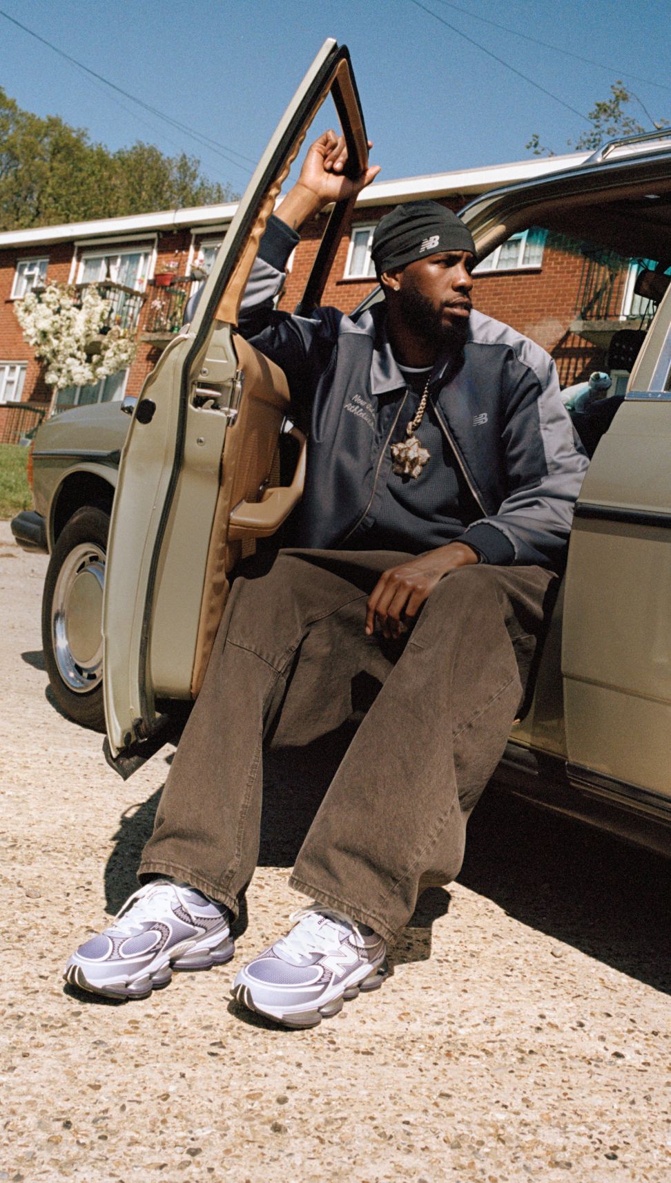 Man sitting in a car with the door open wearing purple New Balance sneakers.