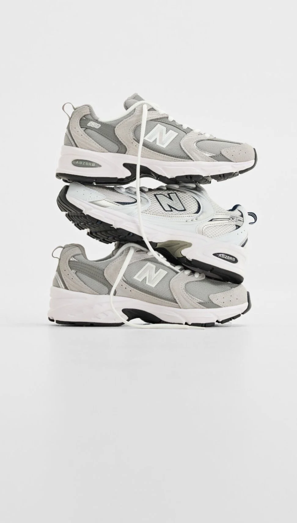 Pile de trois chaussures de sport New Balance sur fond blanc.&nbsp;